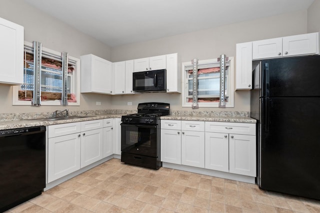 kitchen with white cabinetry, light stone countertops, sink, and black appliances