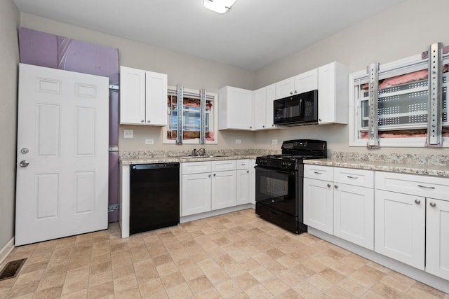 kitchen featuring white cabinetry, sink, light stone counters, and black appliances