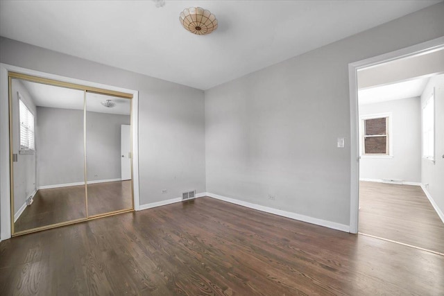 unfurnished bedroom featuring dark wood-type flooring and a closet