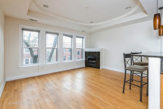 living room with a wealth of natural light, a fireplace, and a tray ceiling