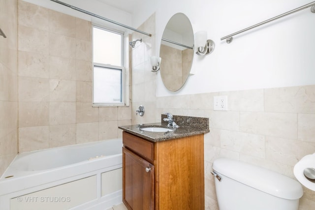 full bathroom featuring tiled shower / bath combo, vanity, tile walls, and toilet