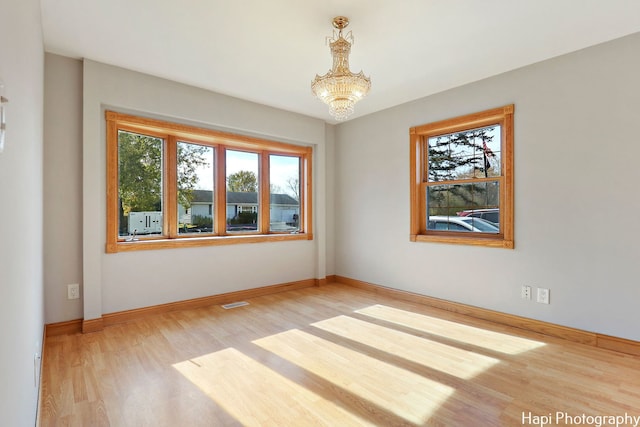 unfurnished room with hardwood / wood-style floors and a chandelier