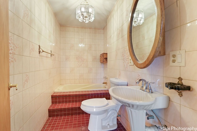 bathroom with tile walls, tile patterned flooring, a relaxing tiled tub, a notable chandelier, and toilet