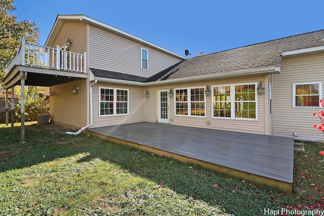 rear view of house featuring central AC, a deck, and a lawn