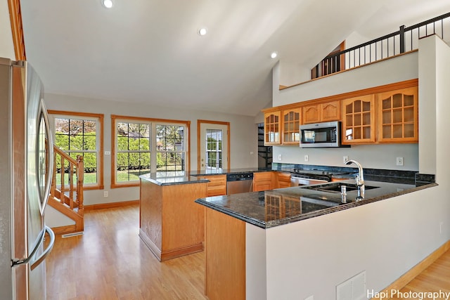 kitchen with appliances with stainless steel finishes, kitchen peninsula, sink, and dark stone countertops