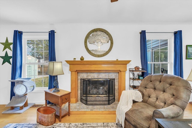 living area with crown molding, a fireplace, and light wood-type flooring