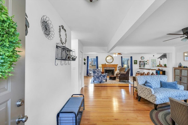 living room featuring beamed ceiling, ceiling fan, and light hardwood / wood-style floors