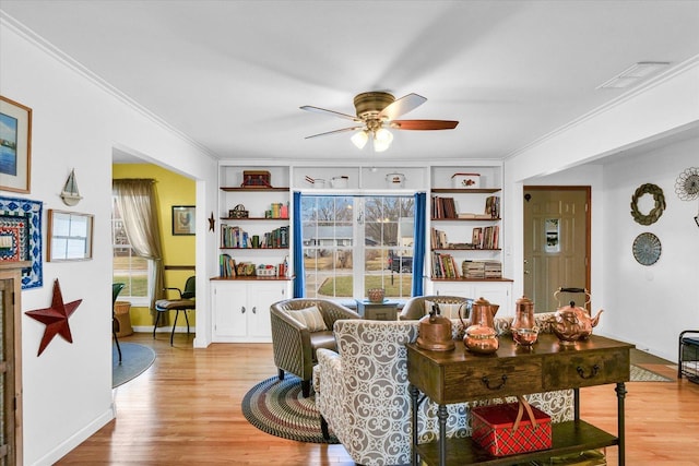 living room with crown molding, ceiling fan, and light wood-type flooring