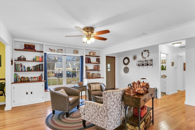 living room featuring crown molding, ceiling fan, and light hardwood / wood-style flooring