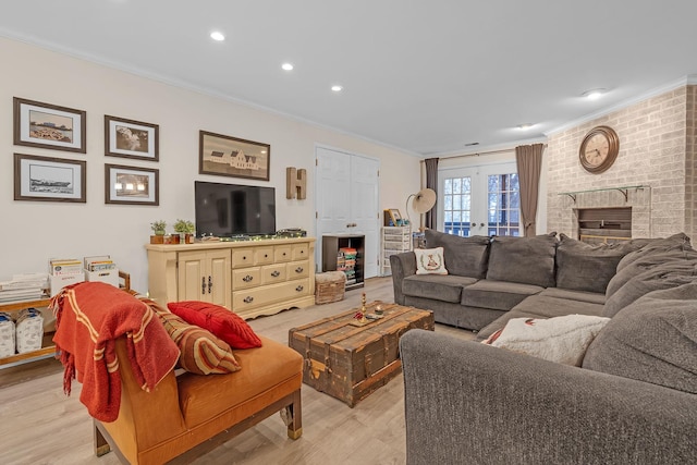 living room featuring crown molding, a fireplace, french doors, and light wood-type flooring