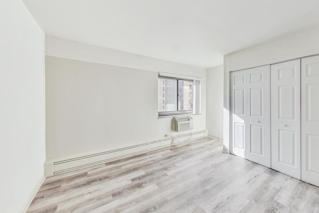 unfurnished bedroom with a baseboard radiator, light hardwood / wood-style floors, a closet, and a wall mounted AC