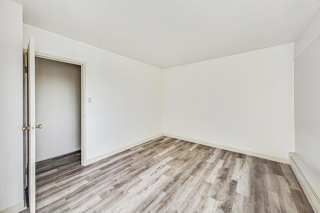 unfurnished room with hardwood / wood-style flooring and a baseboard radiator