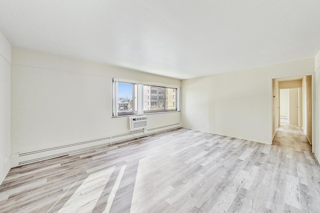 unfurnished room featuring a baseboard heating unit, a wall mounted AC, and light wood-type flooring