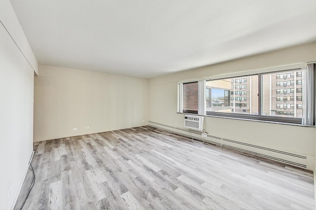 spare room with baseboard heating and light wood-type flooring