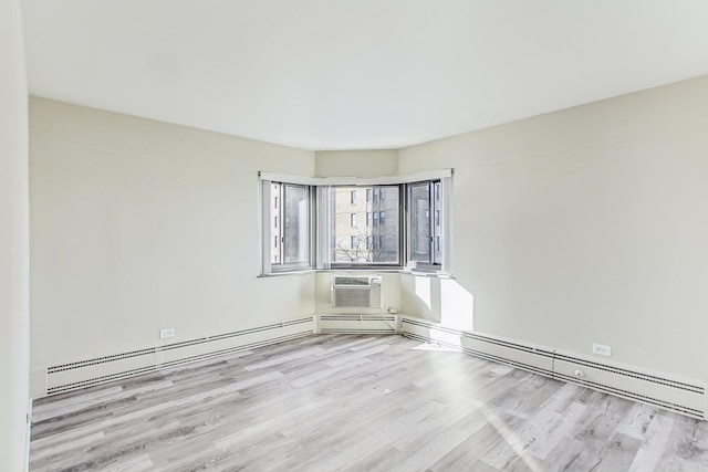 spare room featuring a wall unit AC, baseboard heating, and light wood-type flooring