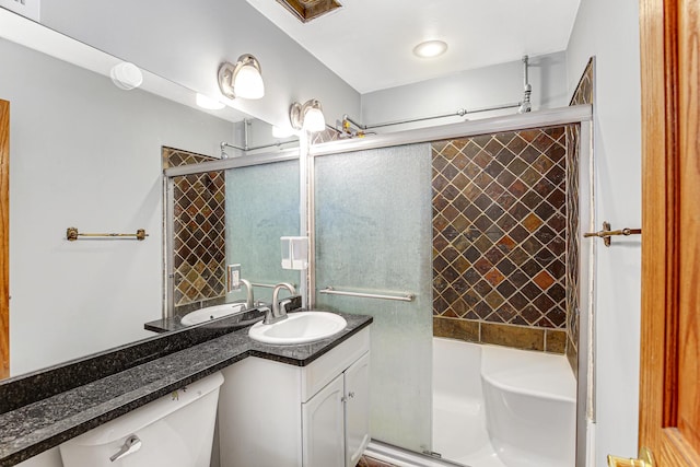 bathroom with a shower with door, vanity, and toilet