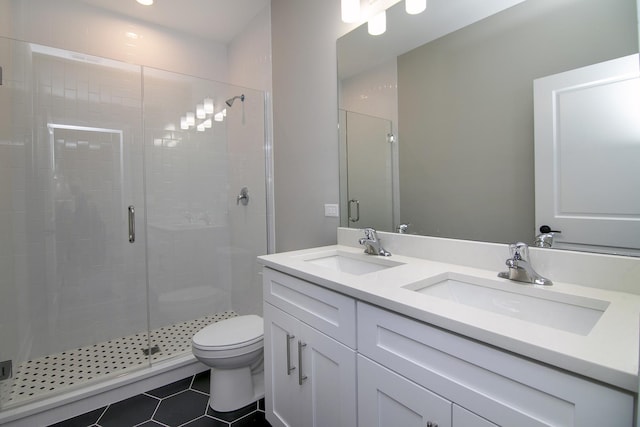 bathroom with tile patterned flooring, vanity, a shower with shower door, and toilet