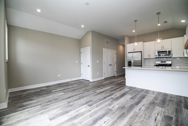 kitchen featuring appliances with stainless steel finishes, pendant lighting, lofted ceiling, white cabinets, and backsplash