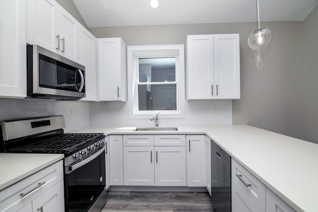 kitchen featuring pendant lighting, stainless steel appliances, sink, and white cabinets