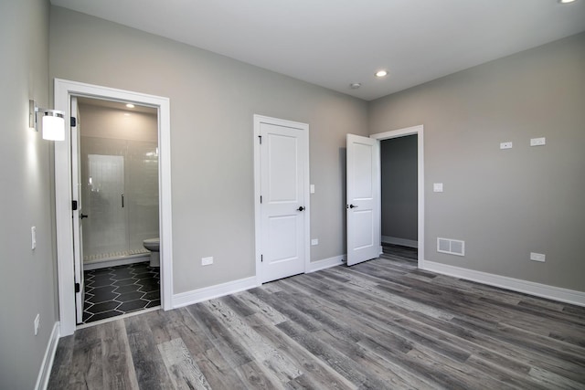 unfurnished bedroom featuring ensuite bath and dark wood-type flooring