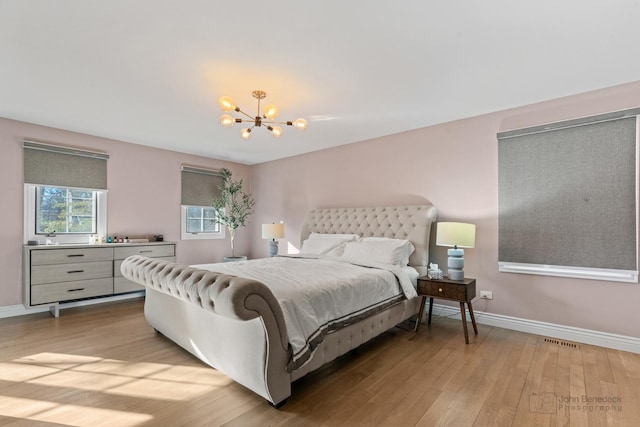 bedroom featuring an inviting chandelier and light hardwood / wood-style flooring