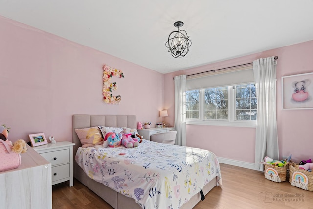 bedroom with hardwood / wood-style floors and a notable chandelier