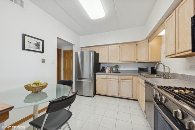 kitchen featuring appliances with stainless steel finishes, sink, light brown cabinets, and light tile patterned floors