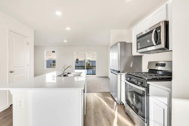 kitchen featuring sink, white cabinetry, appliances with stainless steel finishes, a kitchen island with sink, and light hardwood / wood-style floors