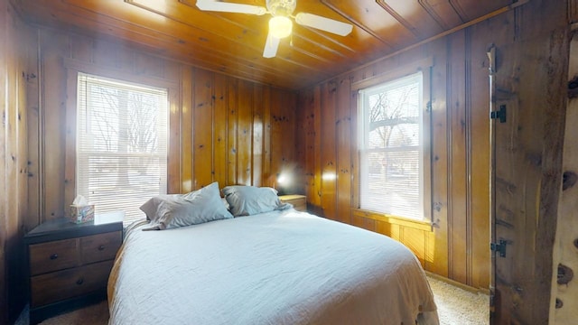 carpeted bedroom with wood ceiling, wooden walls, and ceiling fan