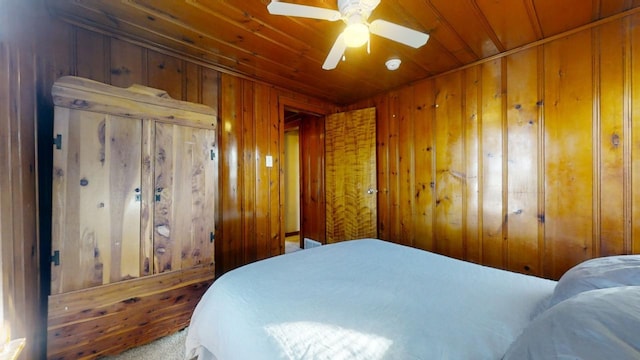 carpeted bedroom featuring wooden ceiling, ceiling fan, and wood walls