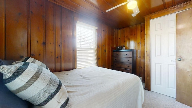 carpeted bedroom with ceiling fan, wood ceiling, and wood walls