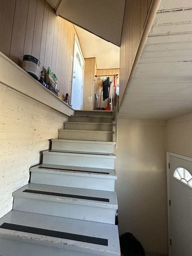 staircase featuring wood walls