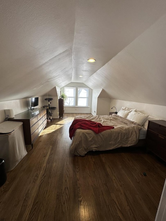 bedroom with lofted ceiling, dark hardwood / wood-style floors, and a textured ceiling