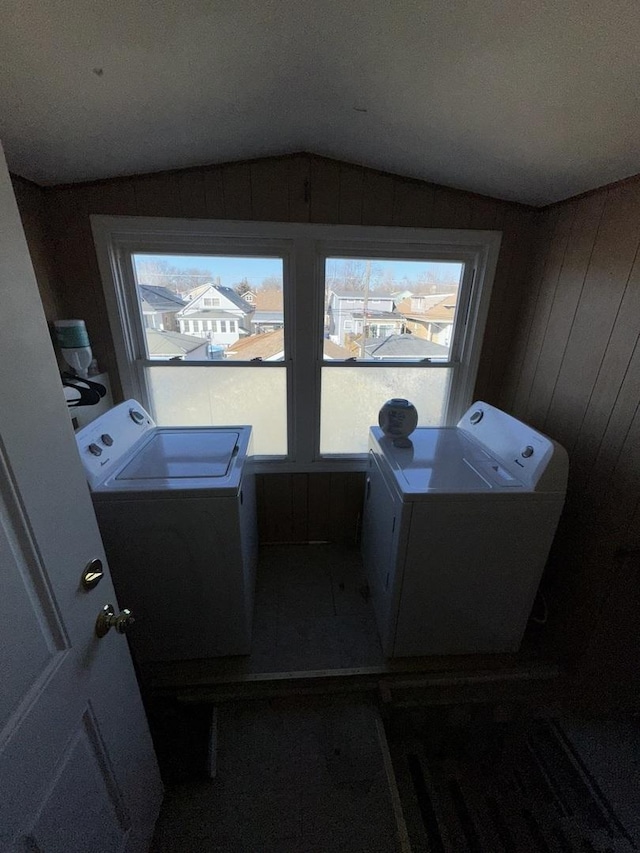 laundry room featuring washing machine and dryer, a wealth of natural light, and wooden walls