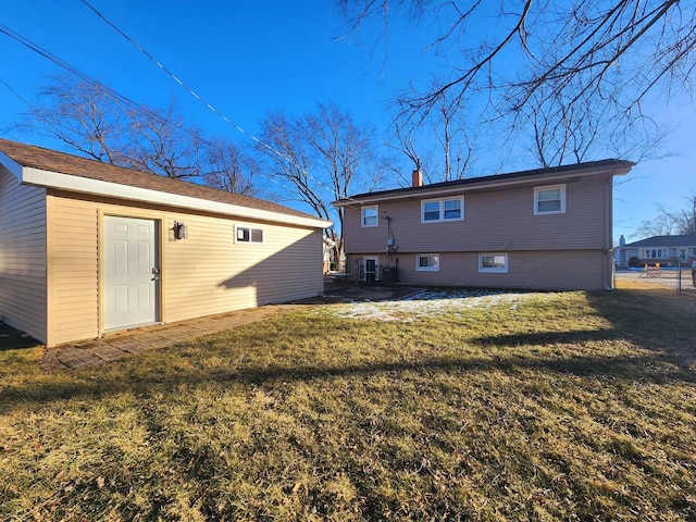 rear view of house featuring an outbuilding and a lawn