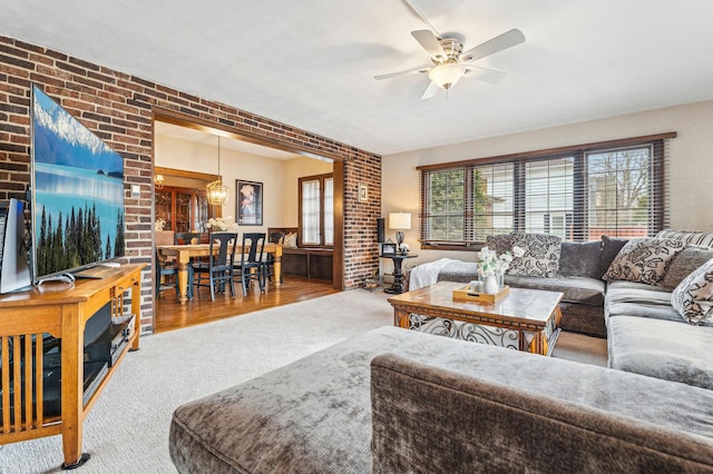 living room with brick wall, ceiling fan, and carpet