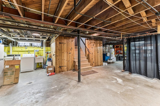 basement featuring water heater, separate washer and dryer, and sink