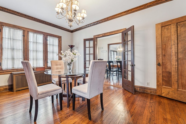 dining room with french doors, crown molding, a chandelier, and hardwood / wood-style flooring