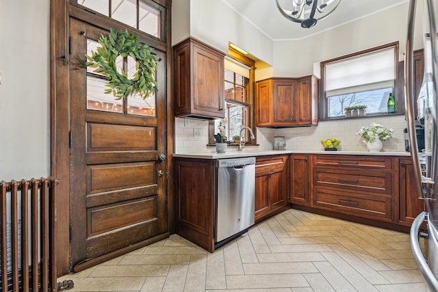 kitchen featuring light parquet floors, appliances with stainless steel finishes, backsplash, radiator heating unit, and ornamental molding