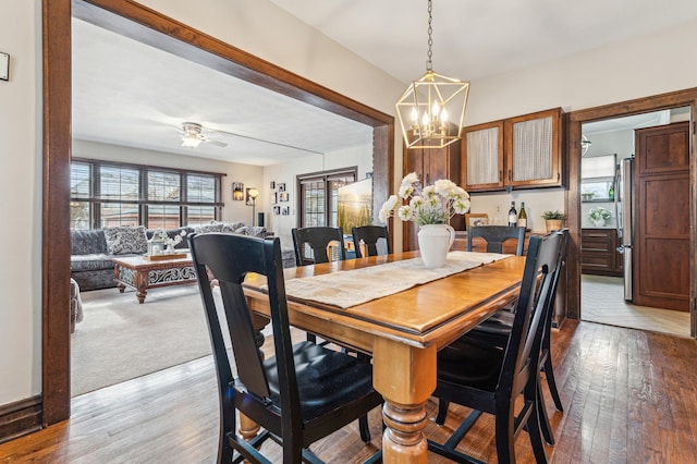 dining space with ceiling fan with notable chandelier and light hardwood / wood-style flooring