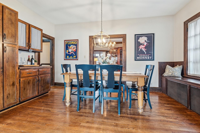 dining area featuring dark wood-type flooring, radiator, and a notable chandelier