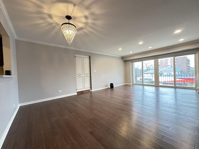 empty room featuring crown molding, dark wood-type flooring, and a notable chandelier