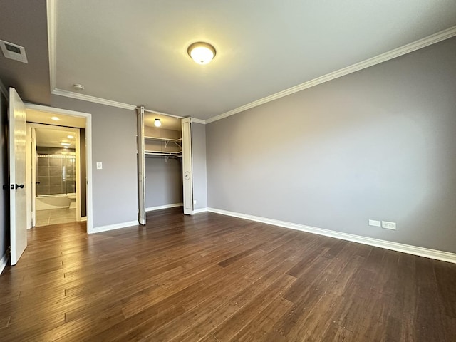 unfurnished bedroom featuring a spacious closet, dark wood-type flooring, ornamental molding, and a closet