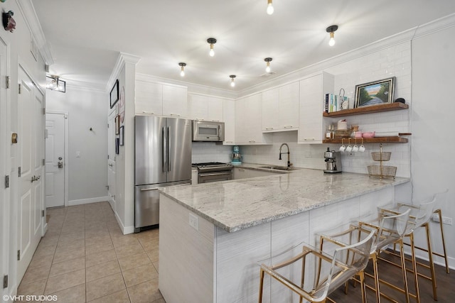 kitchen with sink, white cabinetry, light tile patterned floors, appliances with stainless steel finishes, and kitchen peninsula