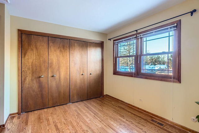 unfurnished bedroom with light hardwood / wood-style flooring and a closet