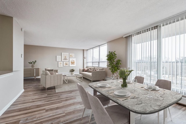 dining area featuring a textured ceiling, wood finished floors, and baseboards