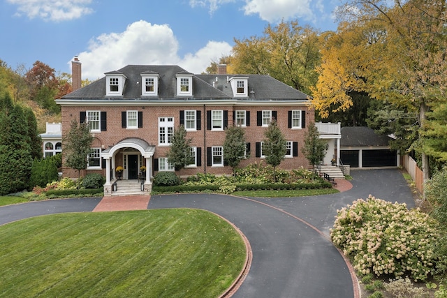 colonial house with a garage, an outdoor structure, and a front yard