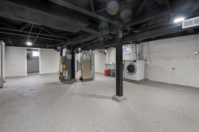 basement with gas water heater, heating unit, separate washer and dryer, sink, and electric panel