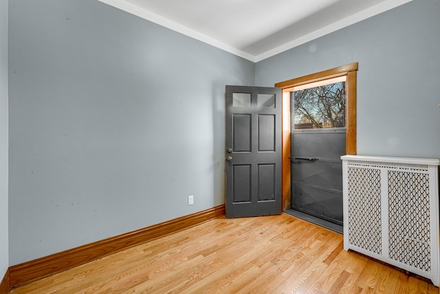 empty room with hardwood / wood-style flooring, ornamental molding, and radiator