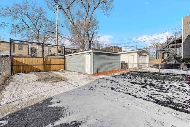 snowy yard featuring a garage and an outdoor structure